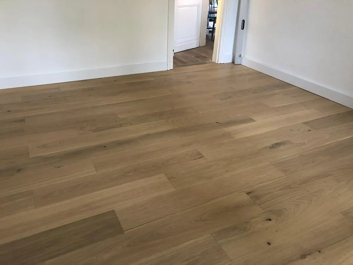 Parquet chêne massif posé dans un salon avec plinthes blanches dans le Loiret
