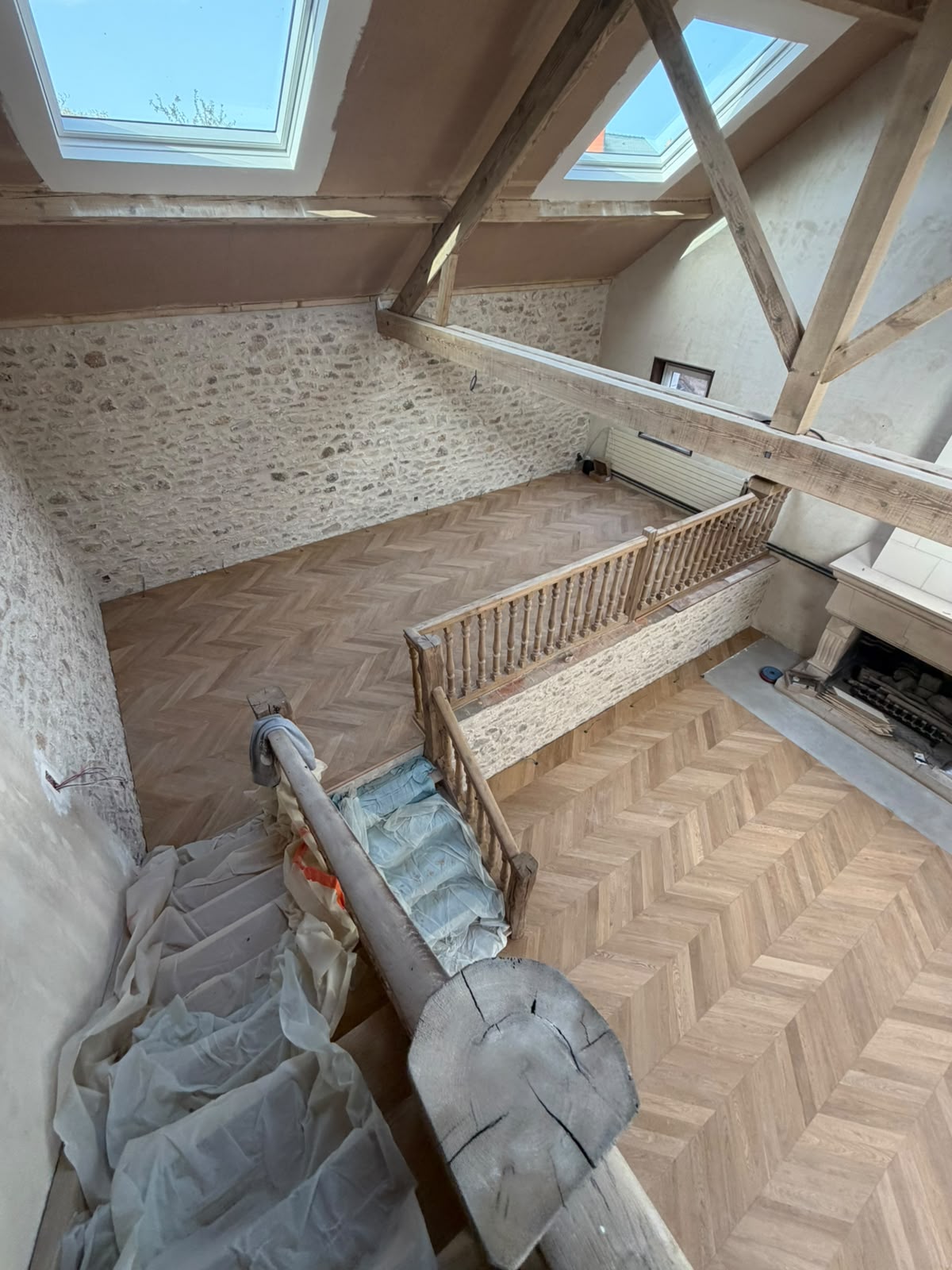 Parquet contrecollé chêne en pointe de Hongrie, posé collé dans un salon sous charpente avec murs en pierre (NATURABOIS, artisan à Orléans)