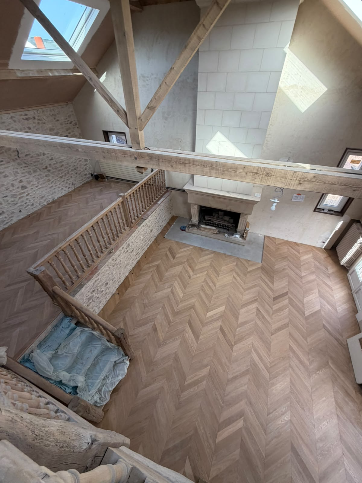 Vue plongeante sur le parquet contrecollé pointe de Hongrie collé, autour d'une cheminée en pierre de taille (NATURABOIS, artisan à Orléans)
