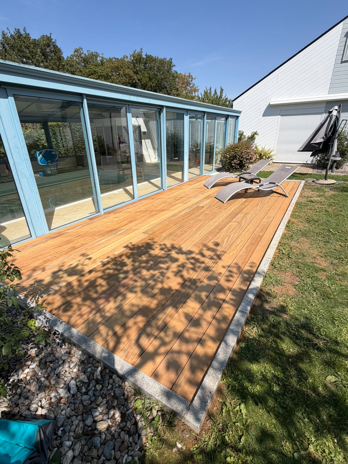 Terrasse en bois exotique garapa posée le long d'une véranda dans le Loiret