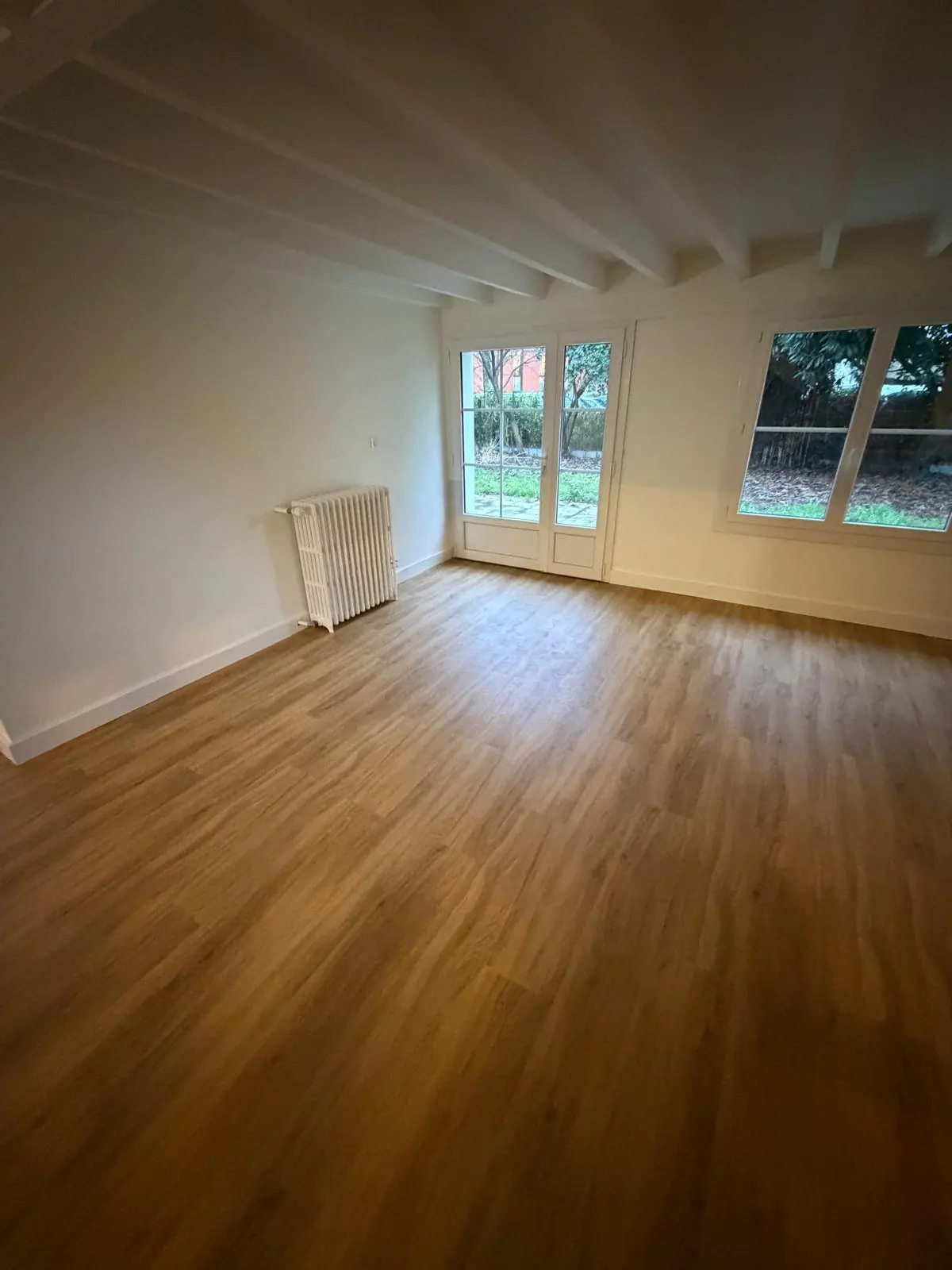 Parquet chêne naturel dans un salon avec poutres apparentes après rénovation